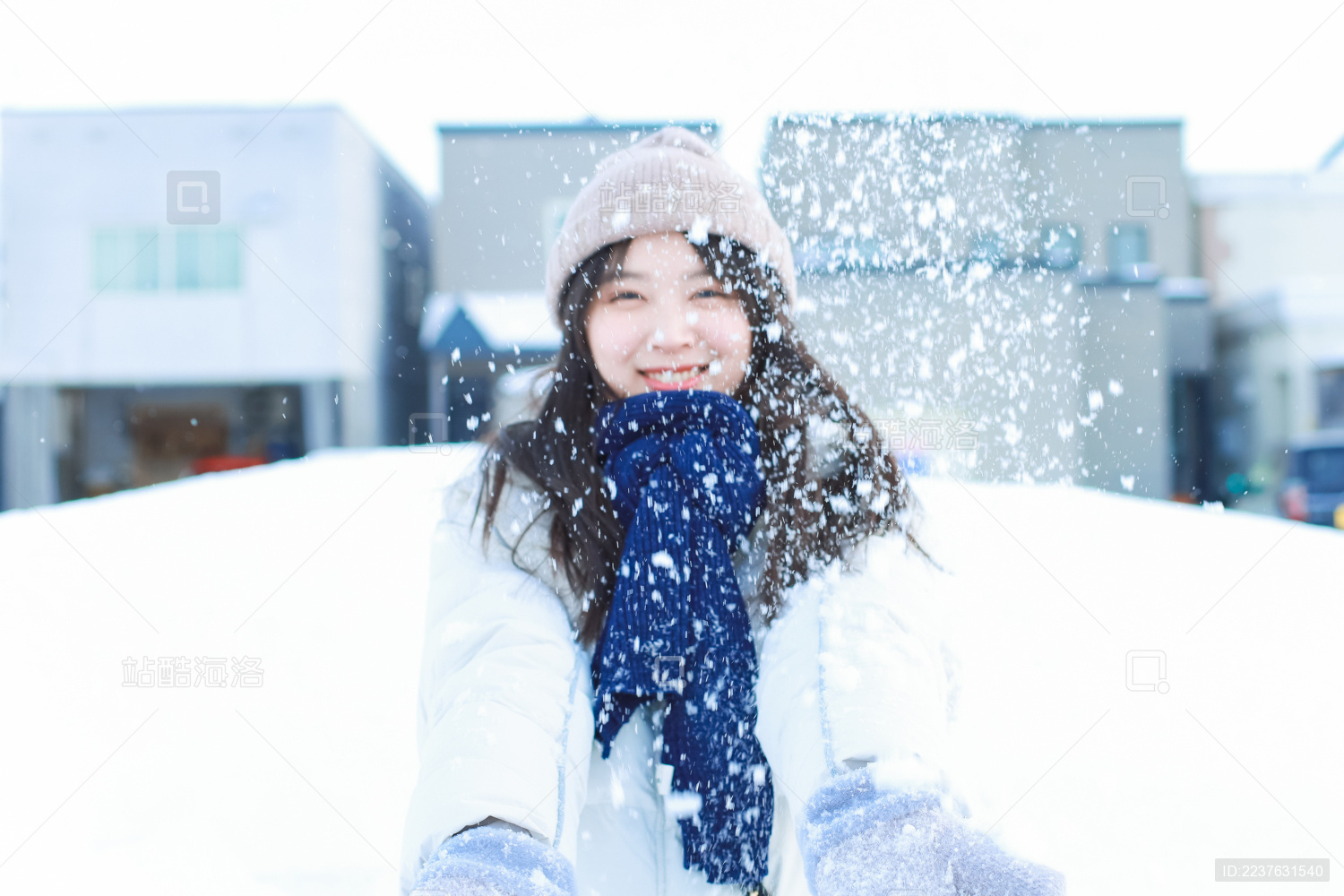 戴帽子的长发亚洲女子在雪地里微笑的撒雪