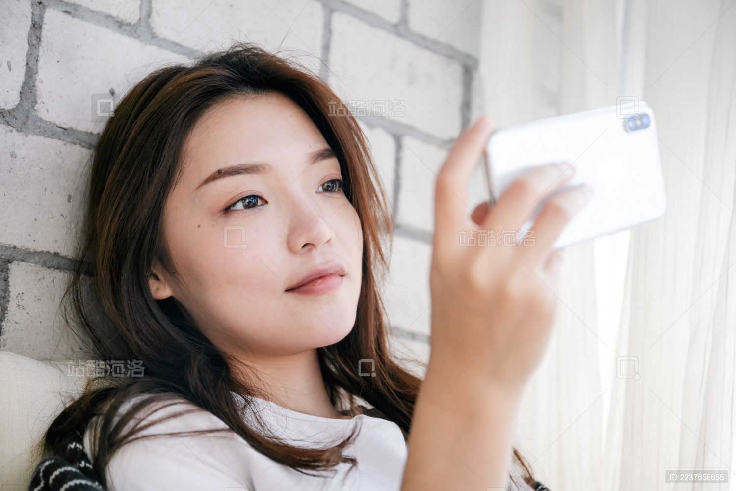 年轻女孩靠在墙边使用手机