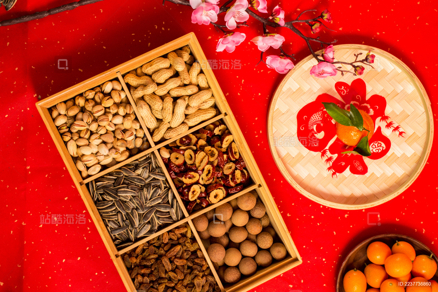 红色背景上装在食盒中的各类干果零食年货
