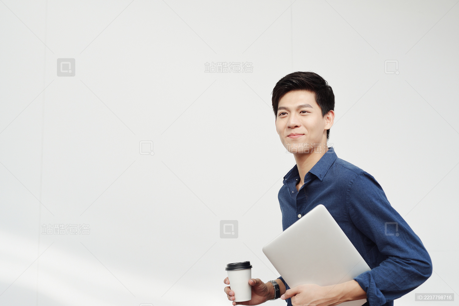 一手抱着笔记本电脑一手拿着咖啡的商务男士