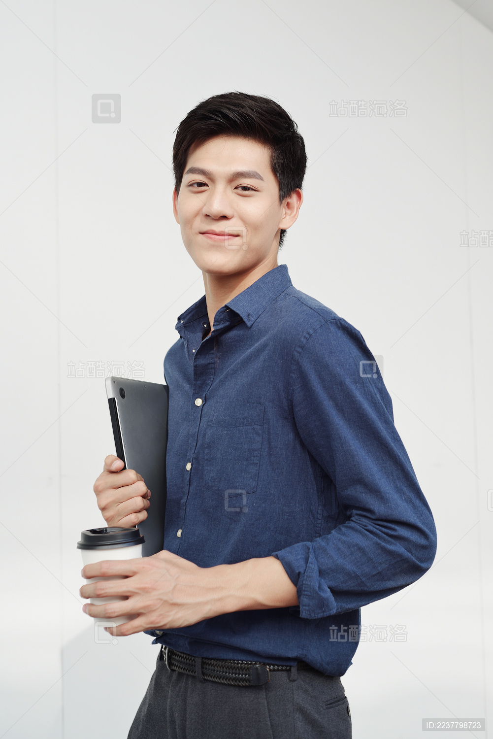 一手抱着笔记本电脑一手拿着咖啡杯商务男士
