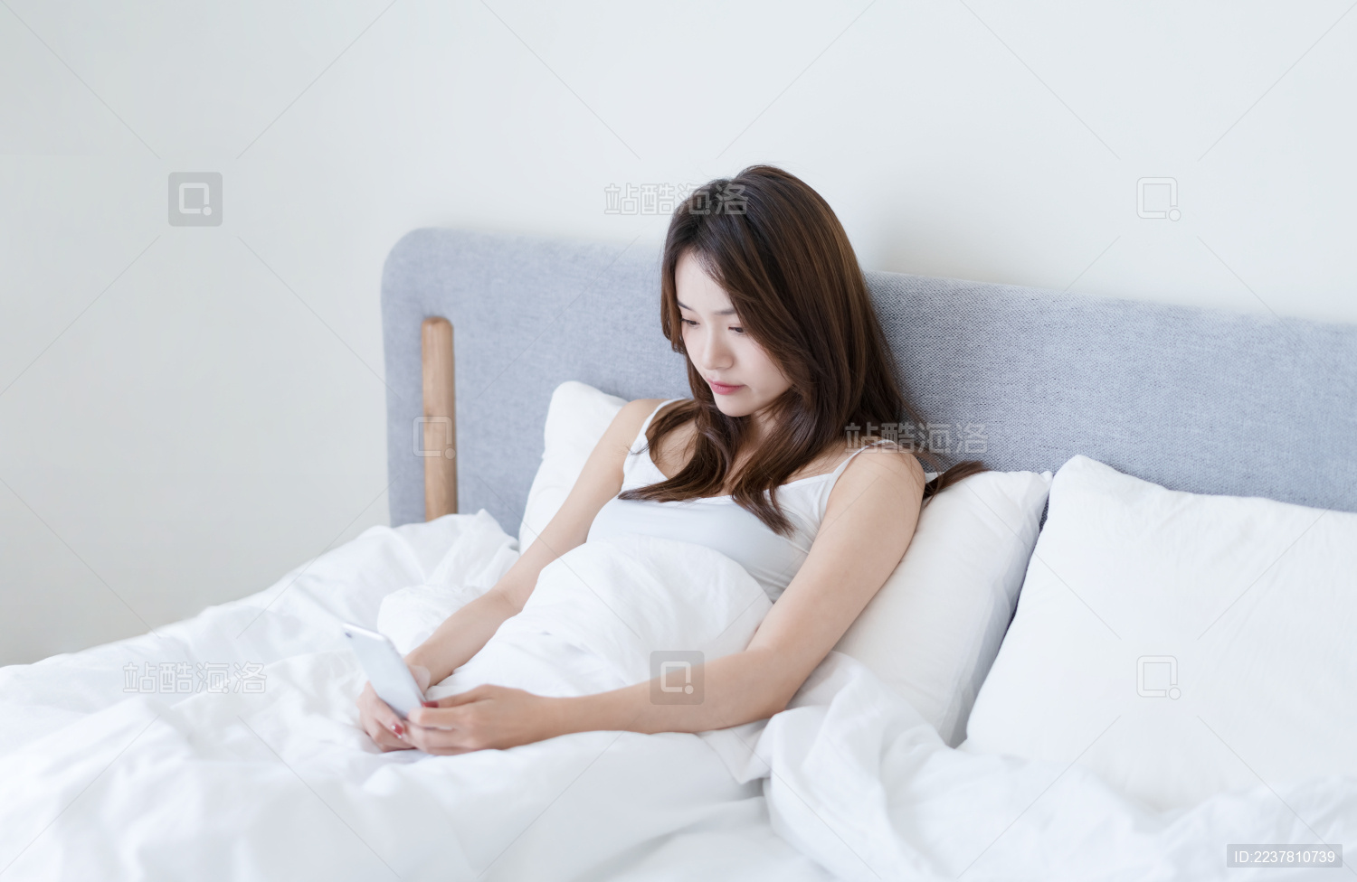 女生坐在床上使用手机