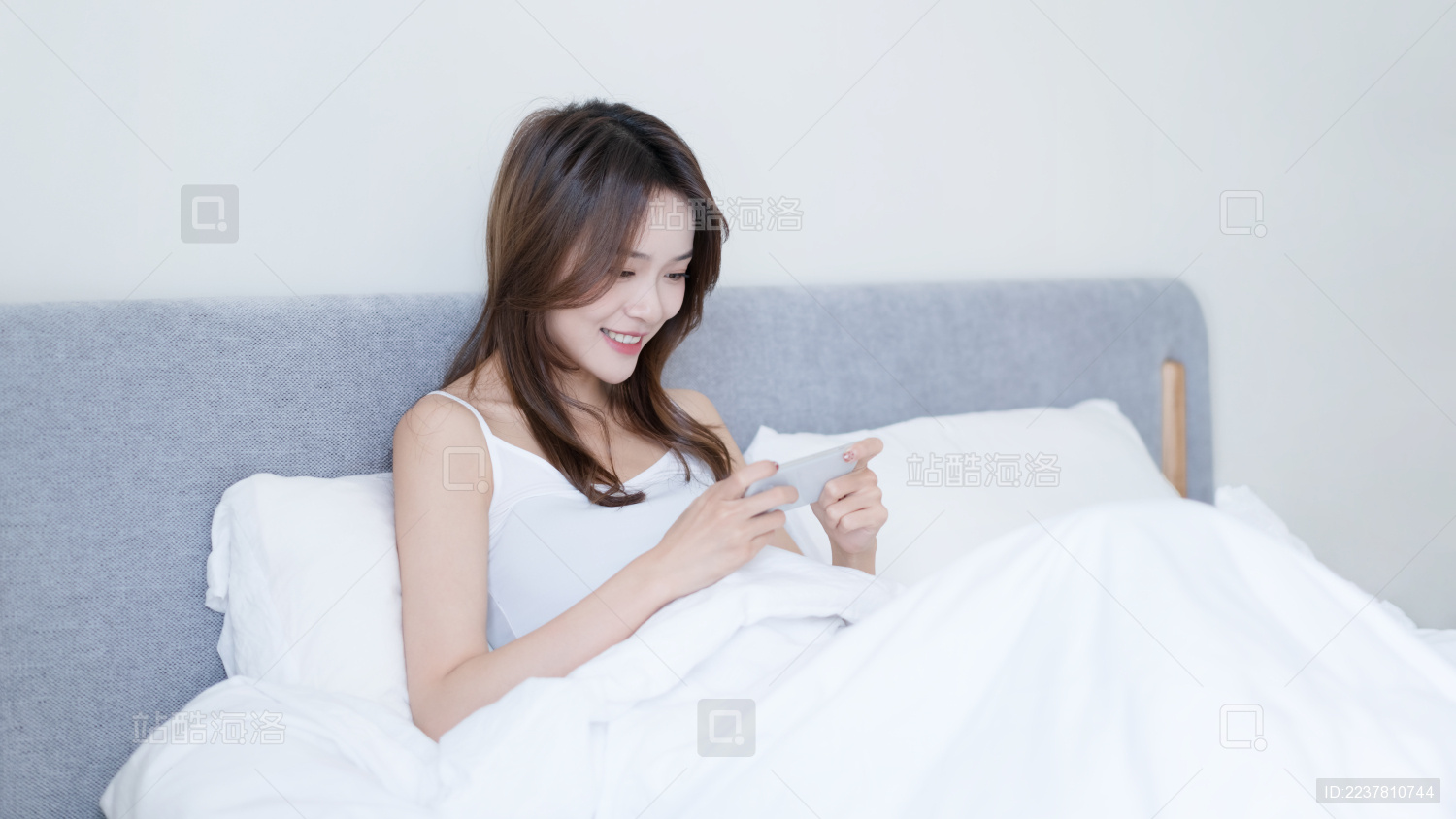 女生坐在床上使用手机