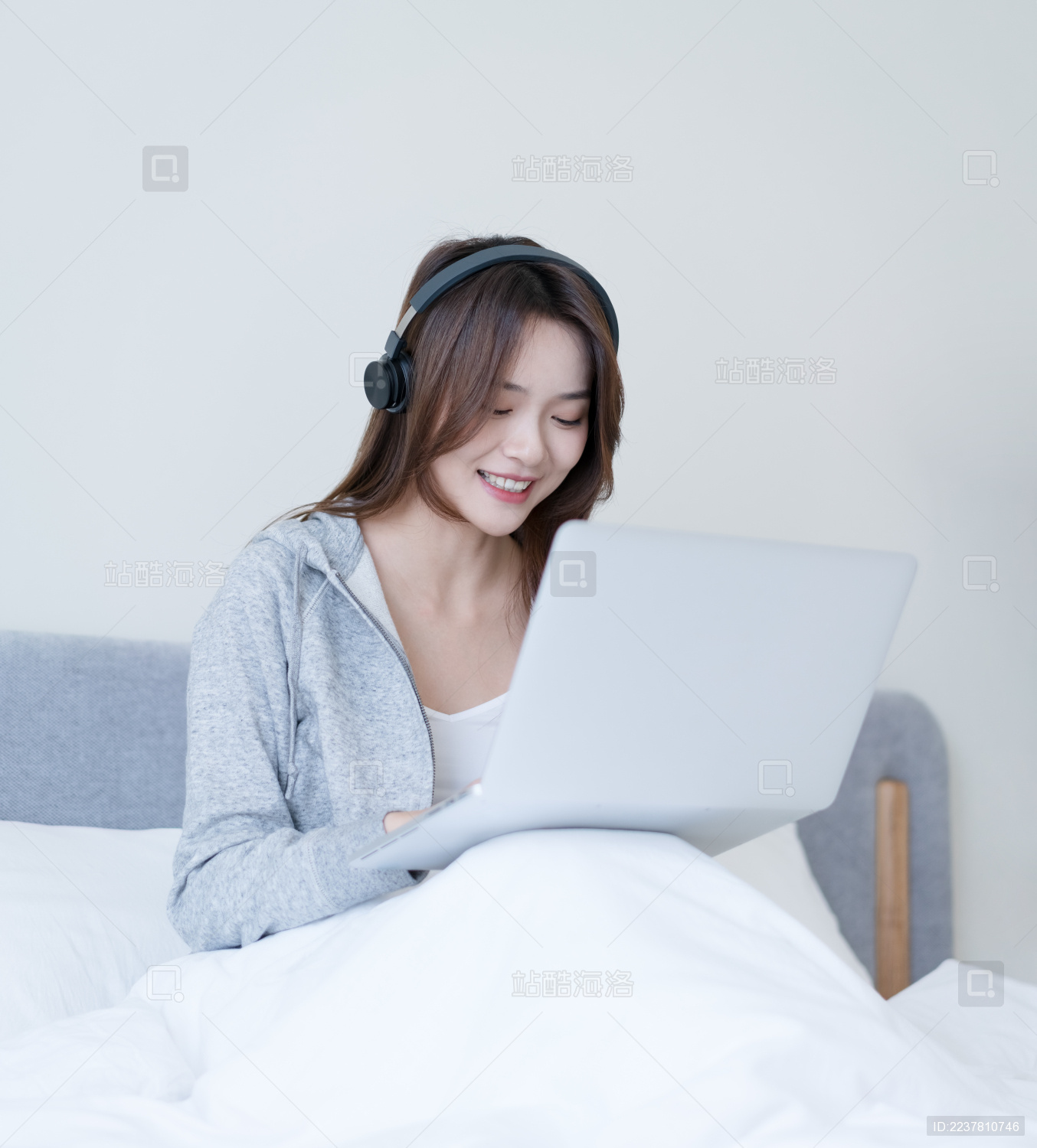 女生坐在床上戴着耳机