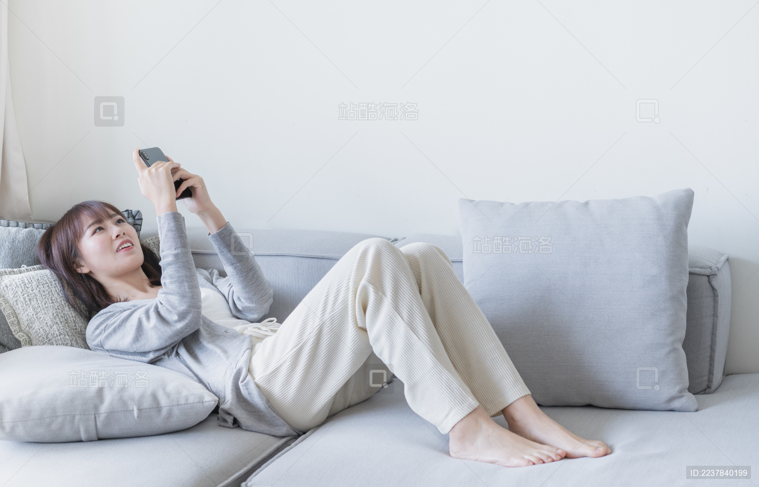 女生躺在沙发上用双手玩手机