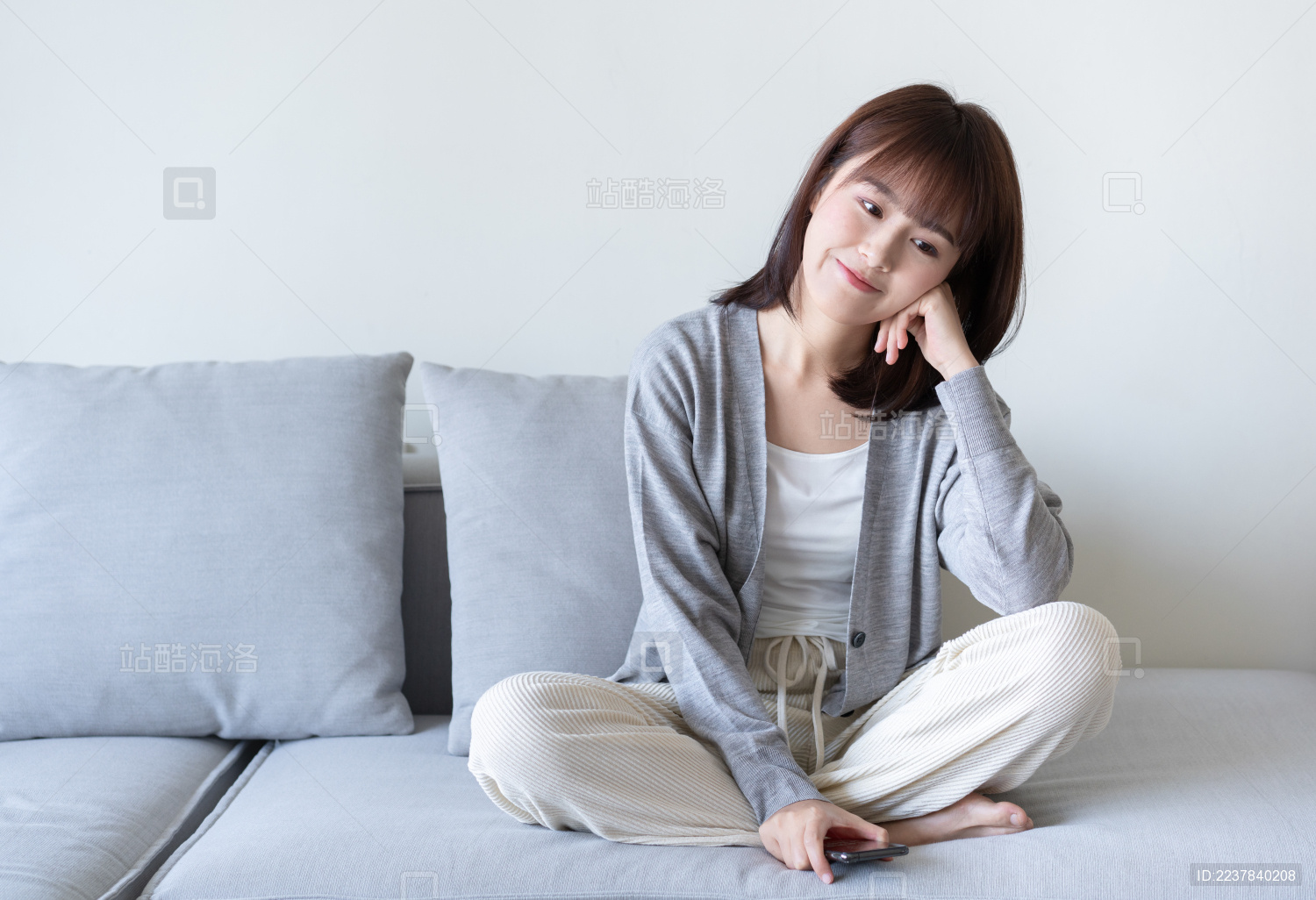 年轻的亚洲女生盘腿坐在沙发上