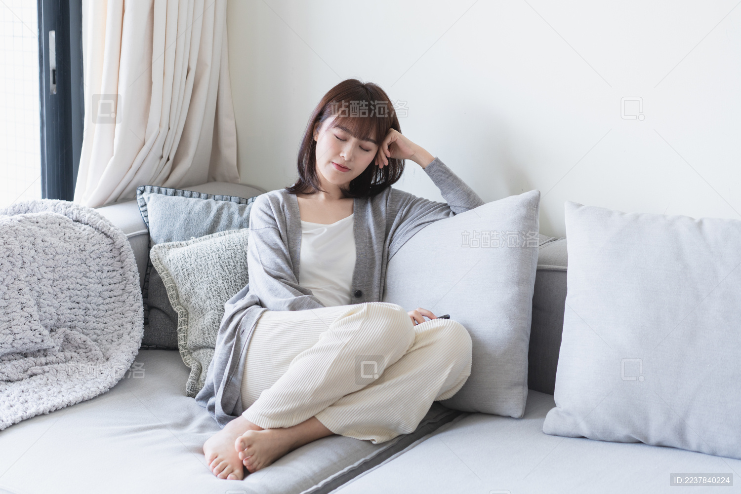 年轻的亚洲女生闭眼靠在沙发上扶着头休息