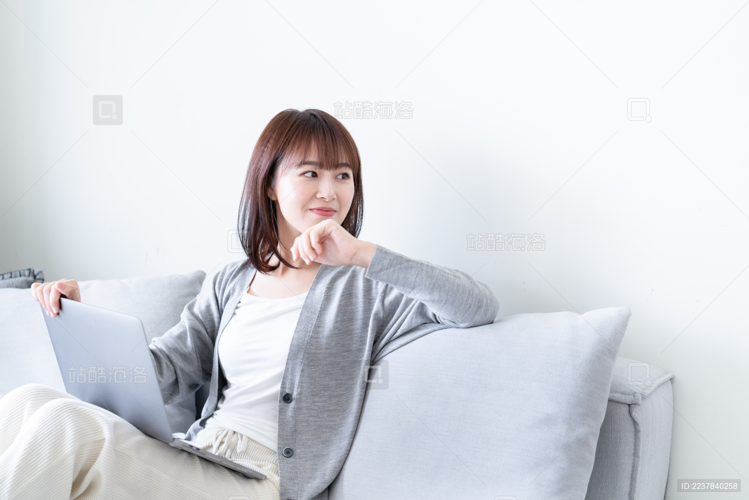 女生坐在沙发上一边看电脑一边思考