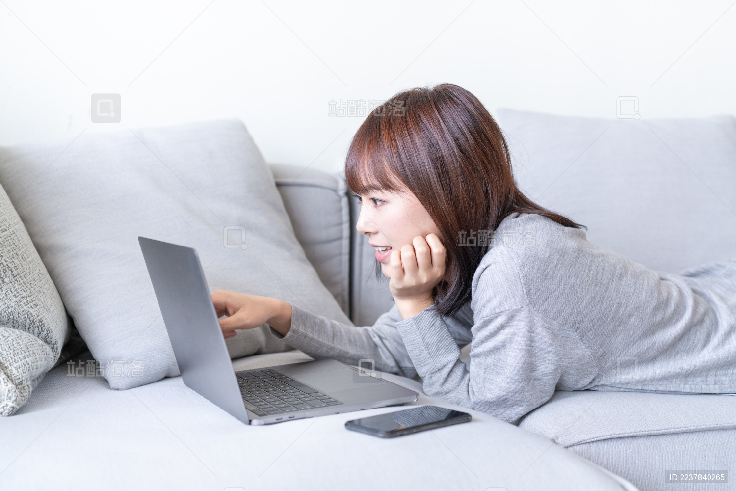 亚洲女生趴在沙发上看电脑