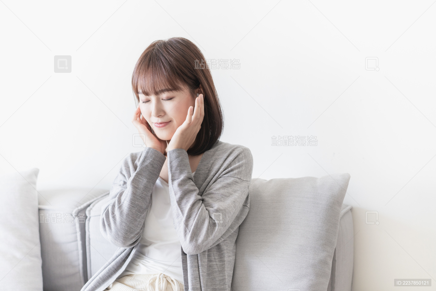 女生坐在沙发上双手扶着耳朵闭眼听音乐