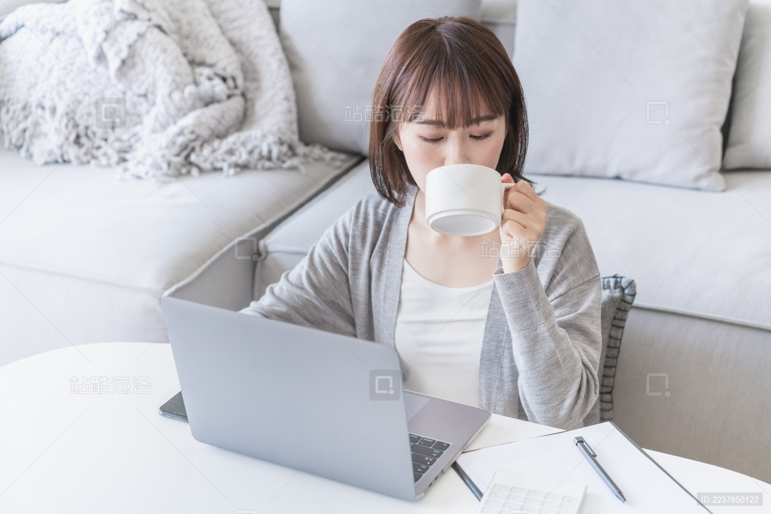 女生在家一边看电脑一边喝水