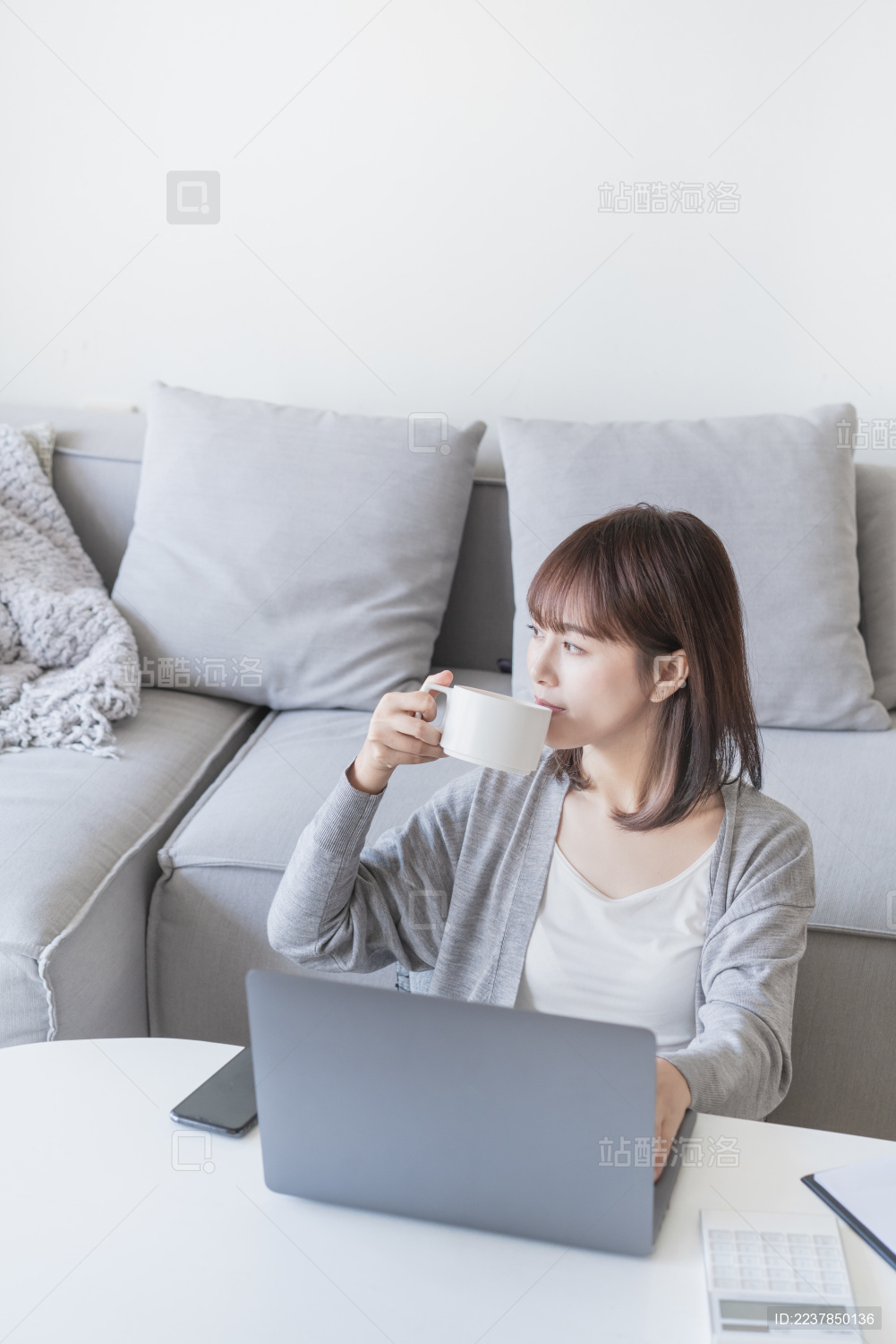 女生在家一边看电脑一边喝水