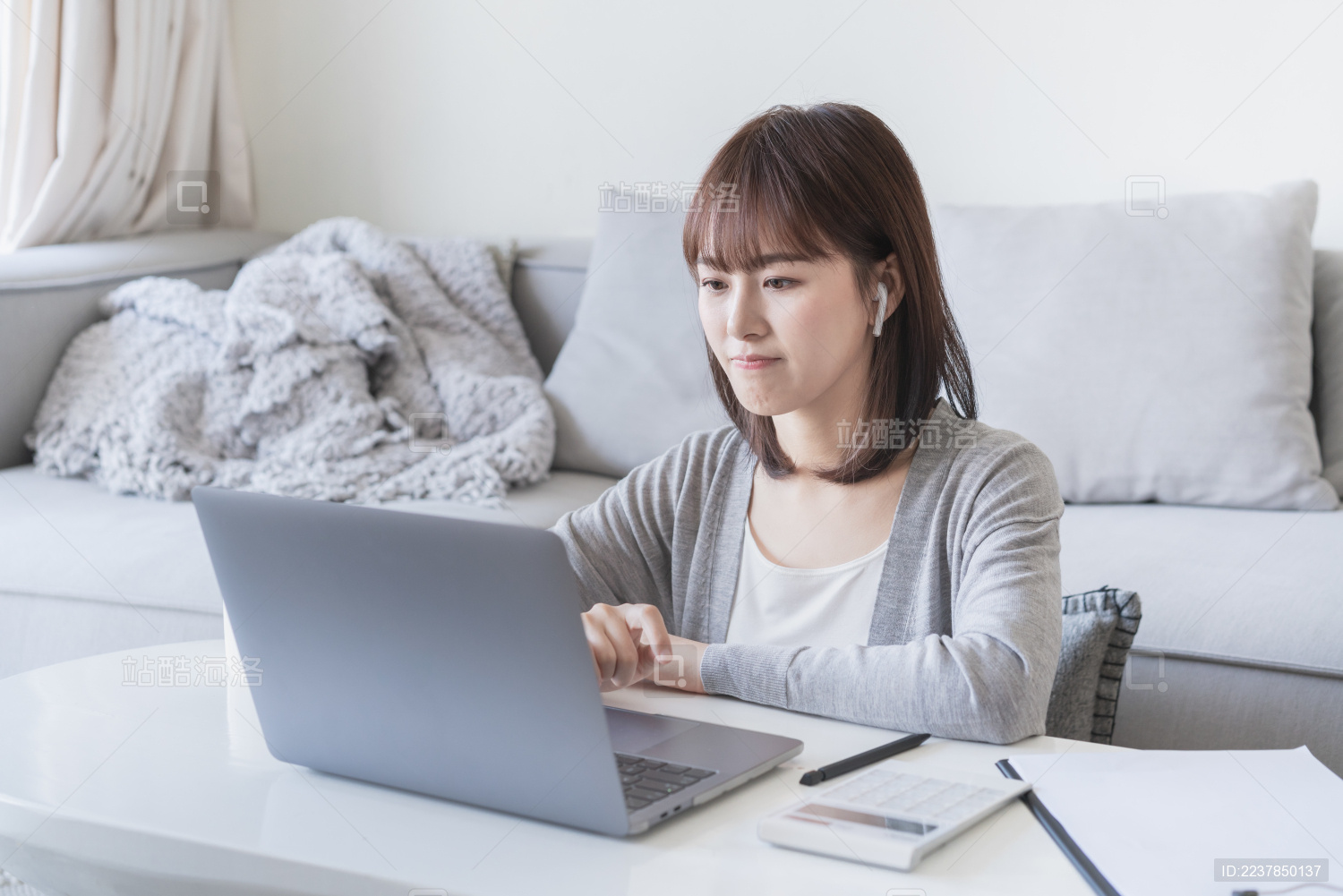 女生坐在客厅带着耳机办公 上网课