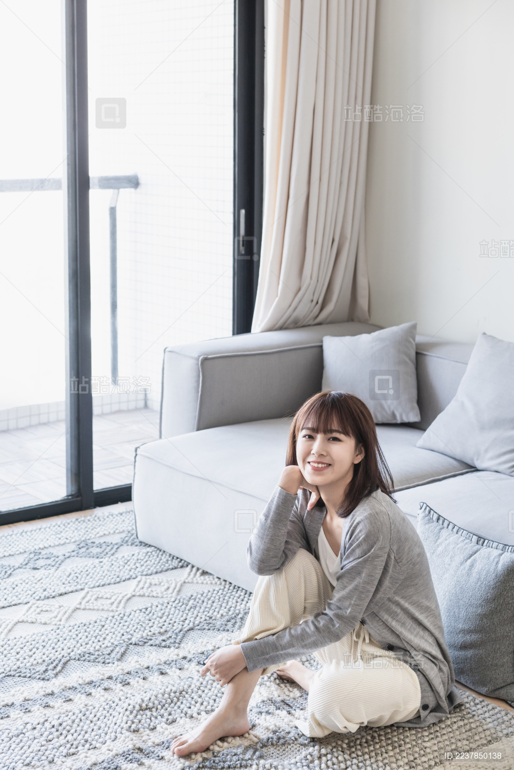 女生坐在客厅地毯上单手扶腿看镜头