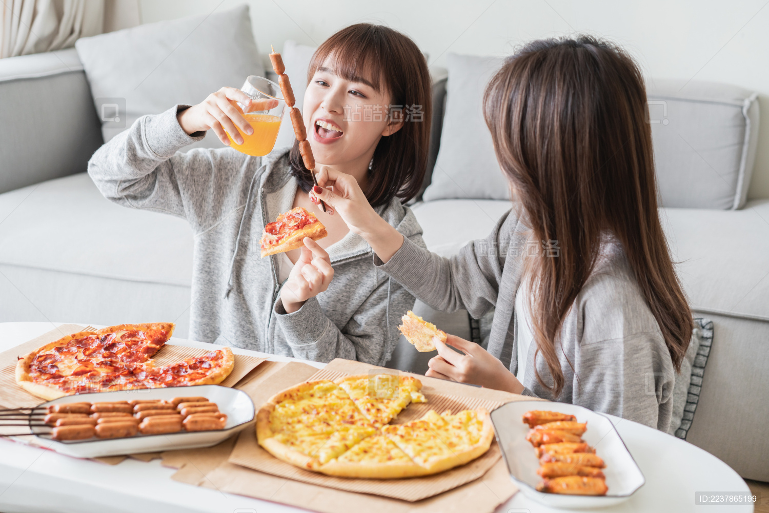 两位年轻亚洲女孩在客厅吃披萨