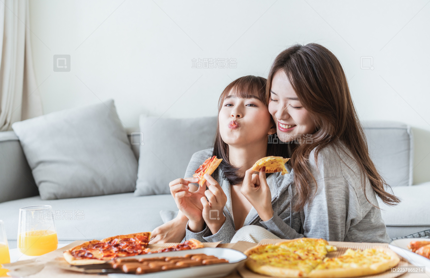 两位年轻亚洲女孩在客厅吃披萨