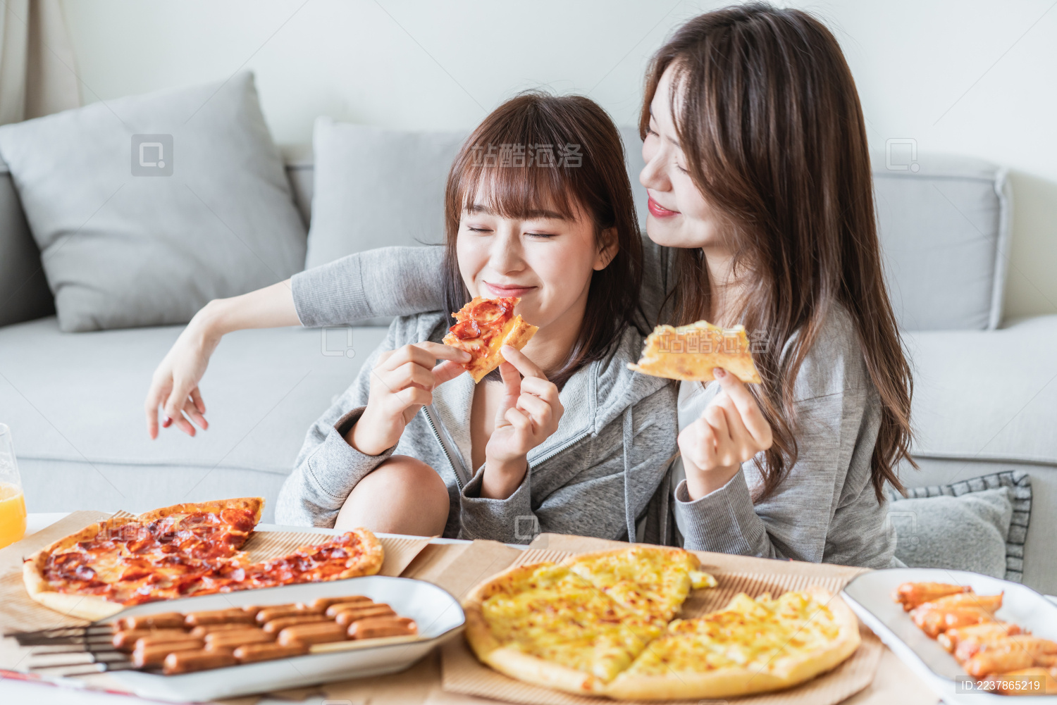 两位年轻亚洲女孩在客厅吃披萨