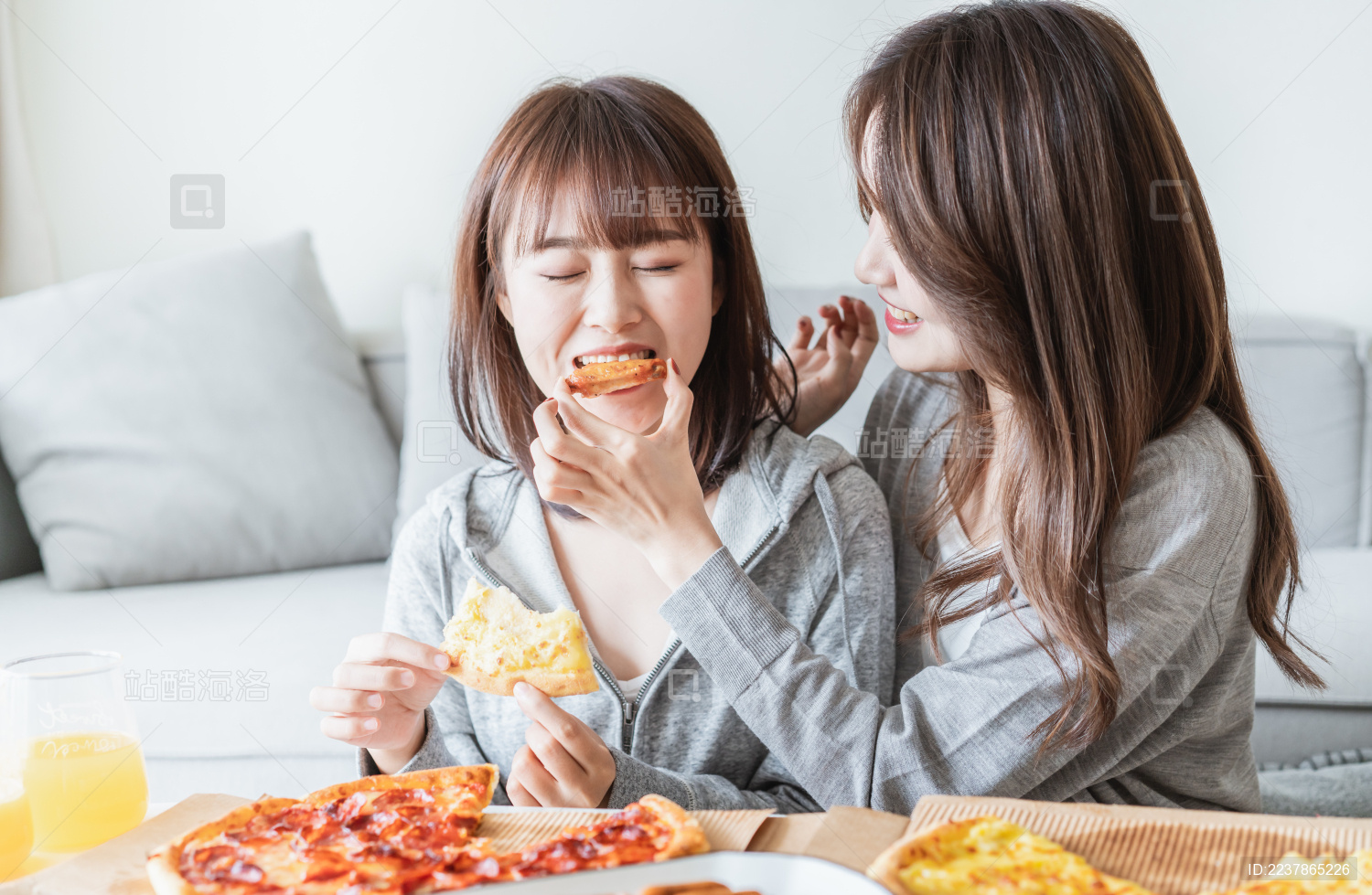 两位年轻亚洲女孩在客厅吃披萨