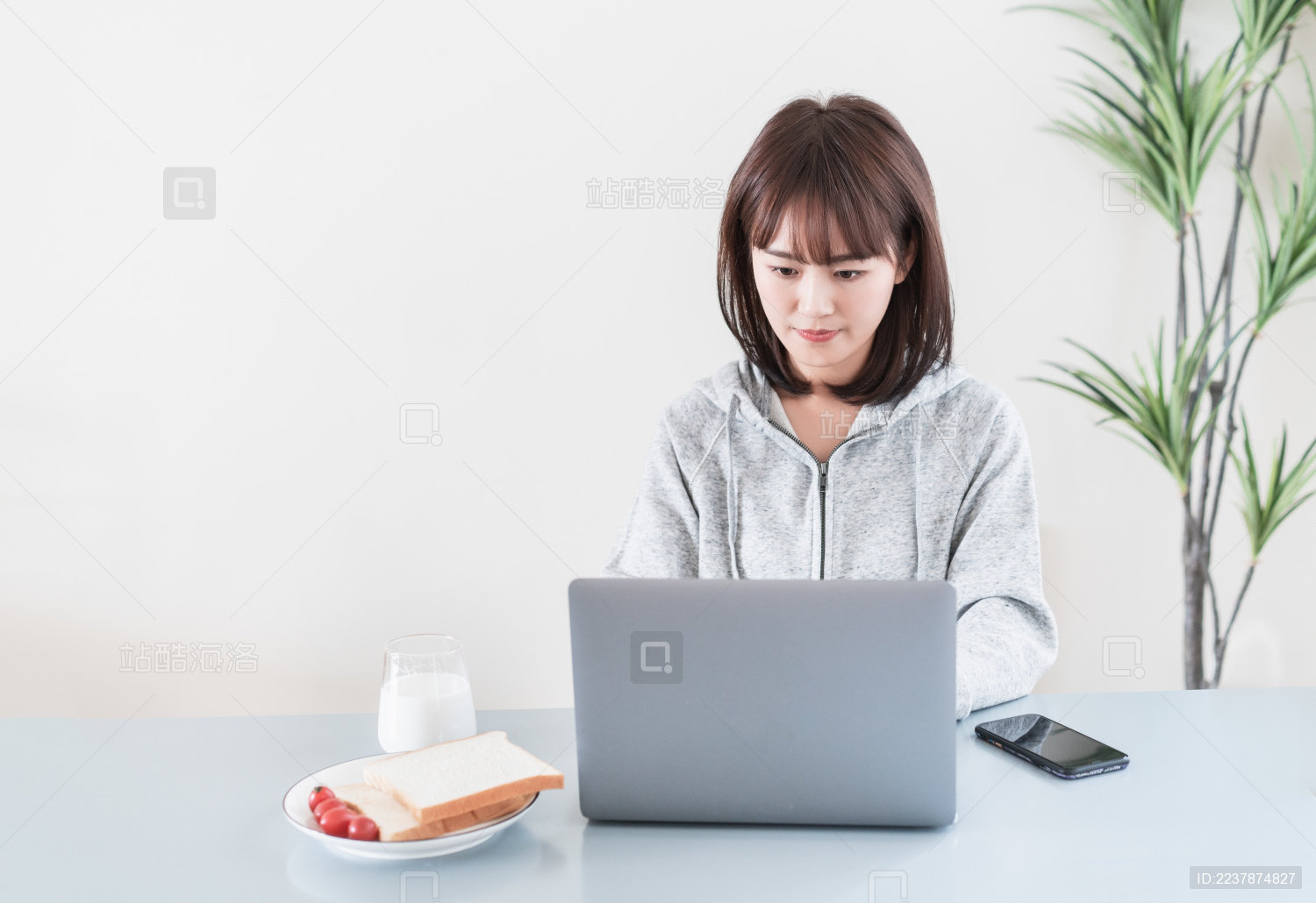 年轻女性一边看电脑一边吃早餐