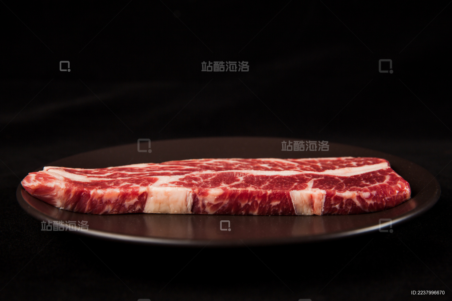 深色背景下放在黑色岩石盘子上的雪花生牛排