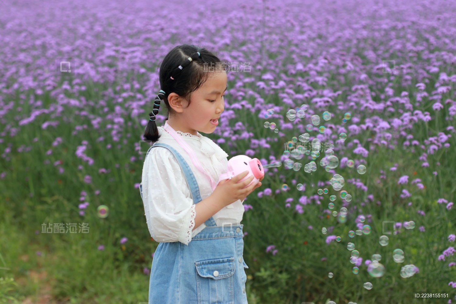 在紫色马鞭草花海中吹泡泡的小女孩