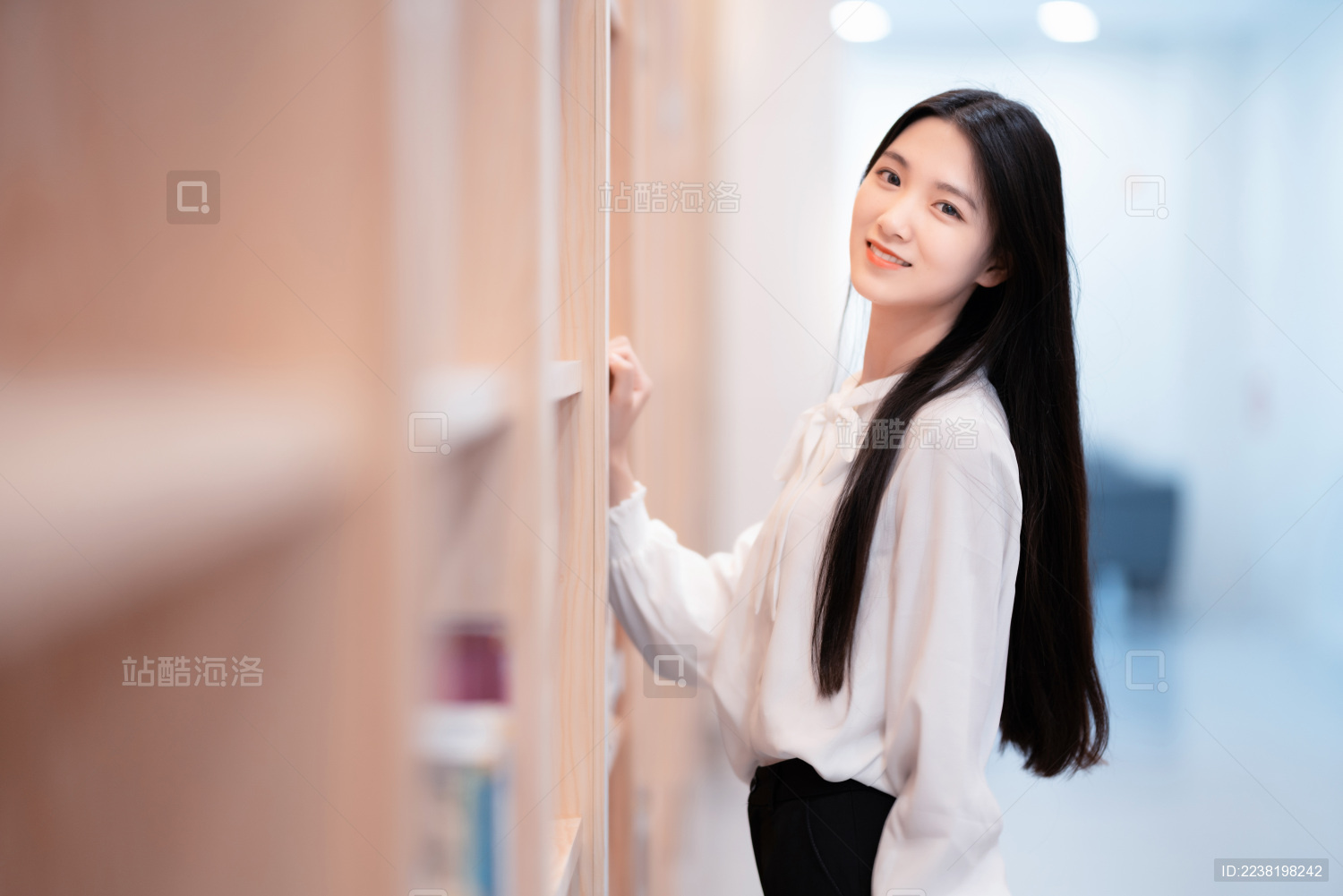 漂亮的女生站在图书馆书架前
