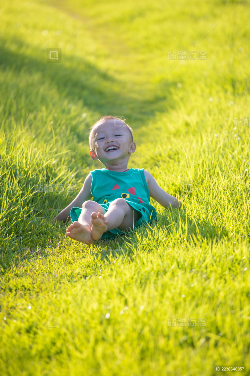 穿绿衣服在草坪上玩耍的小男孩