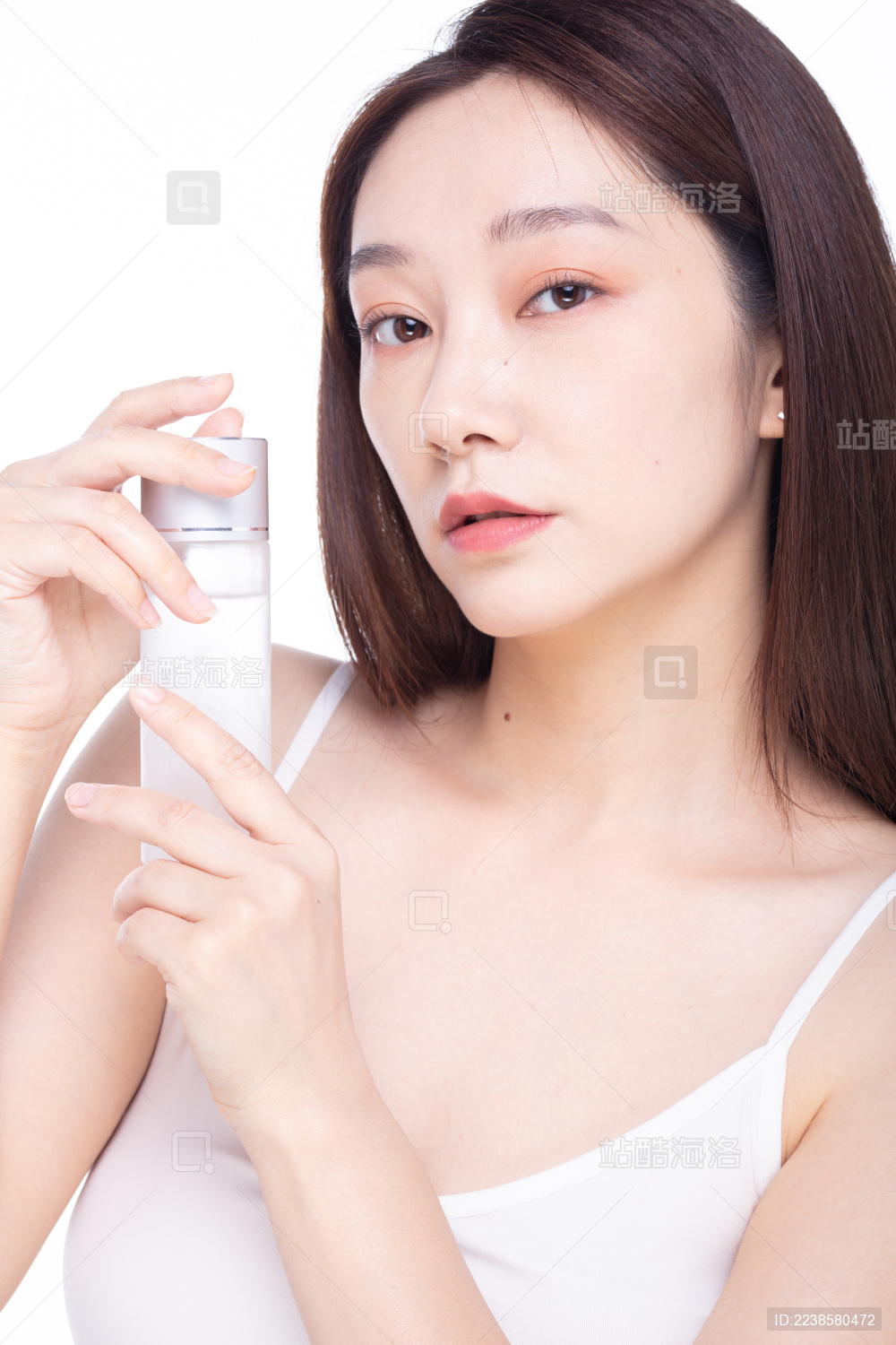 白色背景前使用护肤品的女性