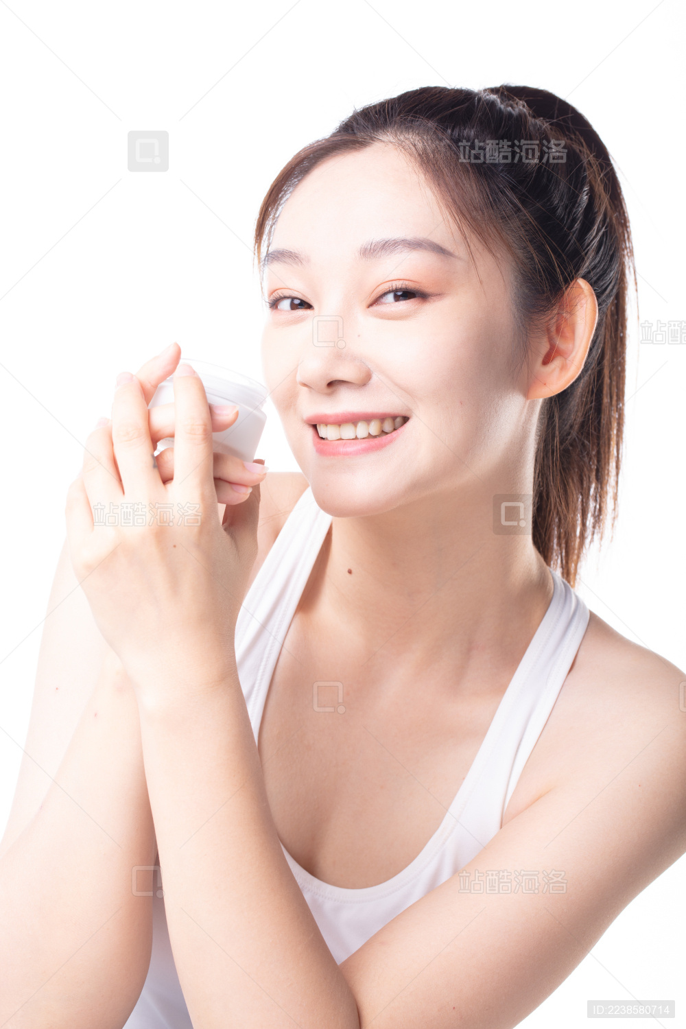 白色背景前使用护肤品的女性