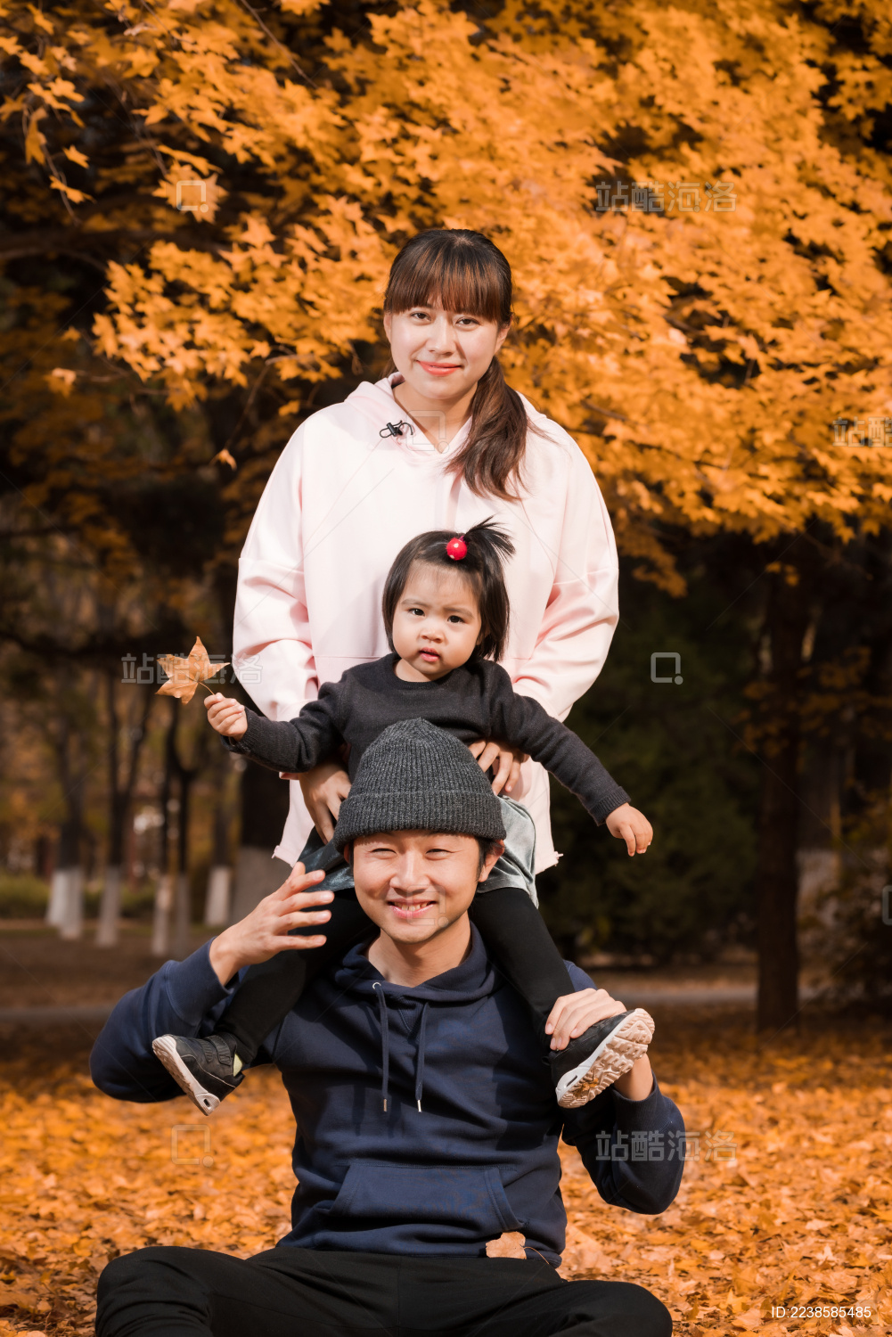 深秋在公园草地上的年轻父母和孩子