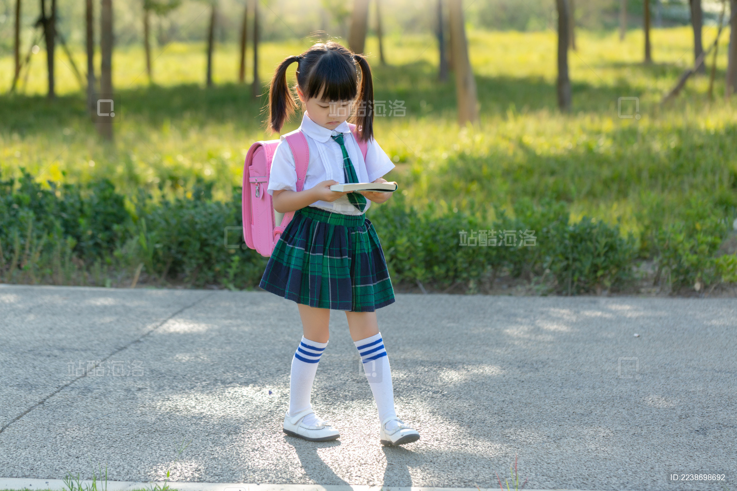 微笑的女生背着书包，手里拿着笔记本和笔在户外。照片摄影图片_ID:425904368-Veer图库