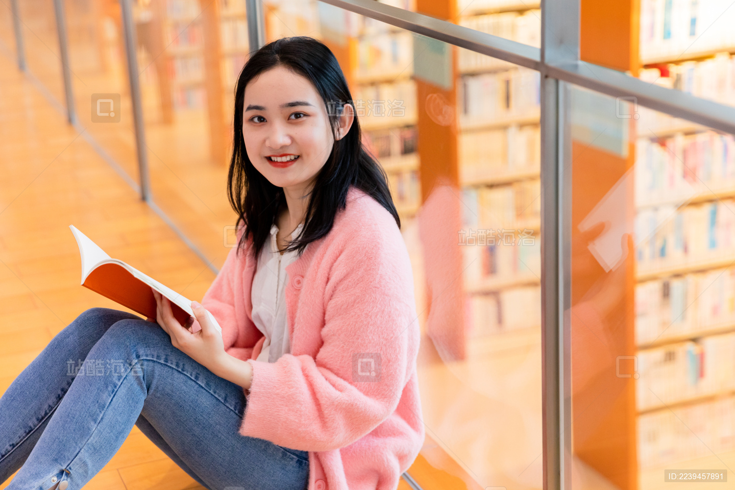 年轻女性坐在图书馆里微笑看镜头