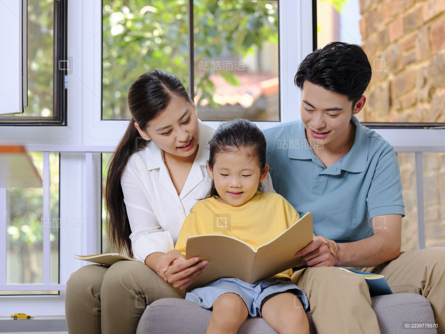 快乐的三口之家坐在沙发上看书