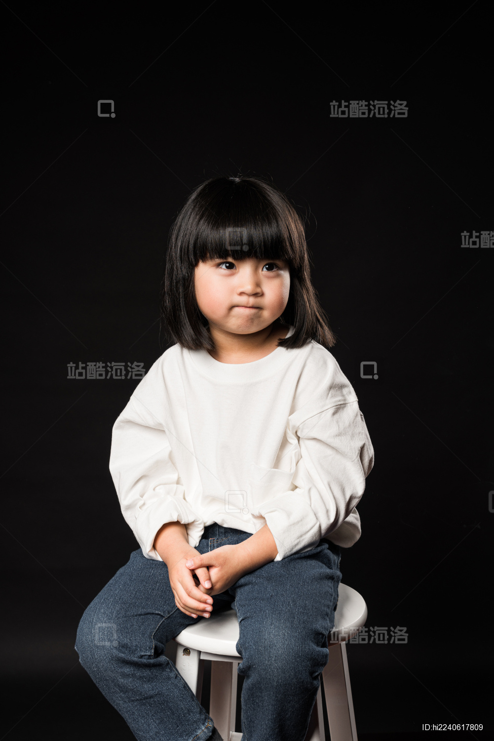 坐在黑背景前玩耍的亚裔女孩