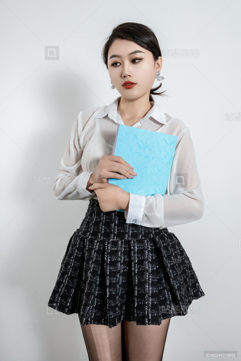 穿着百褶裙的女生抱着一本书看