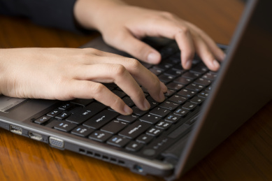 一位女士在使用笔记本电脑的手部特写