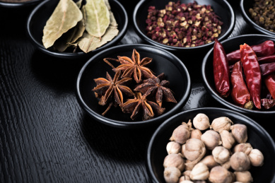 放在黑色盘中的辣椒、八角、花椒、香叶、豆蔻等香辛料