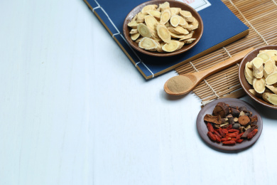 中药材和古代医书放在白色桌面上