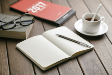 笔记本、2017台历、咖啡杯、书本、眼镜放在复古木头桌面上