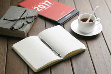 笔记本、2017台历、咖啡杯、书本、眼镜放在复古木头桌面上