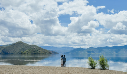 一对年轻中国情侣站在岸边背对镜头依偎看向远方 云南丽江大落水村