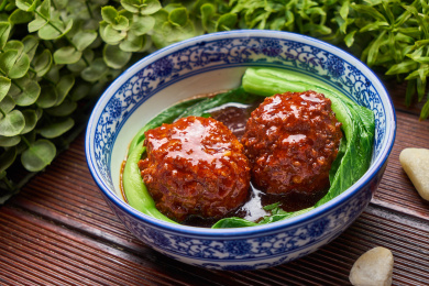 两颗红烧狮子头盛放在蓝边瓷碗里面