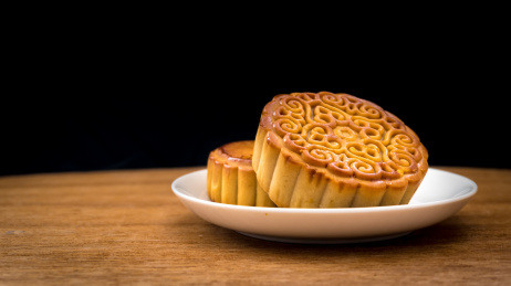 桌子上放在碟子里的两块月饼，黑色背景