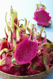 堆起的新鲜火龙果在盘子里，有整个和切开的