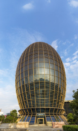 蓝天白云下金黄色的椭圆形芽胚造型大楼