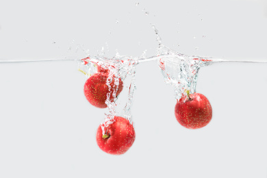 白色背景下三颗山楂柿坠入水中