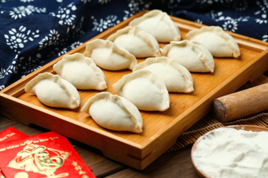 饺子，擀面杖，面粉，福字红包放在木桌上