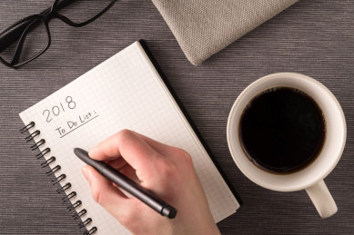 咖啡杯、眼镜和正在书写的新年计划