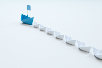 领导的概念，红色折纸船领先白色船。