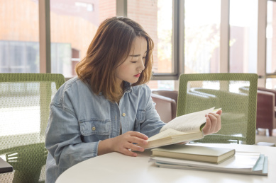 年轻美丽的女孩在桌子前看书